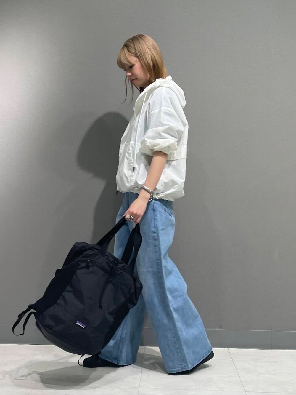 ブルー系のデニムパンツ、ホワイト系のパーカーを着用したレディースの春コーディネートの4枚目の写真