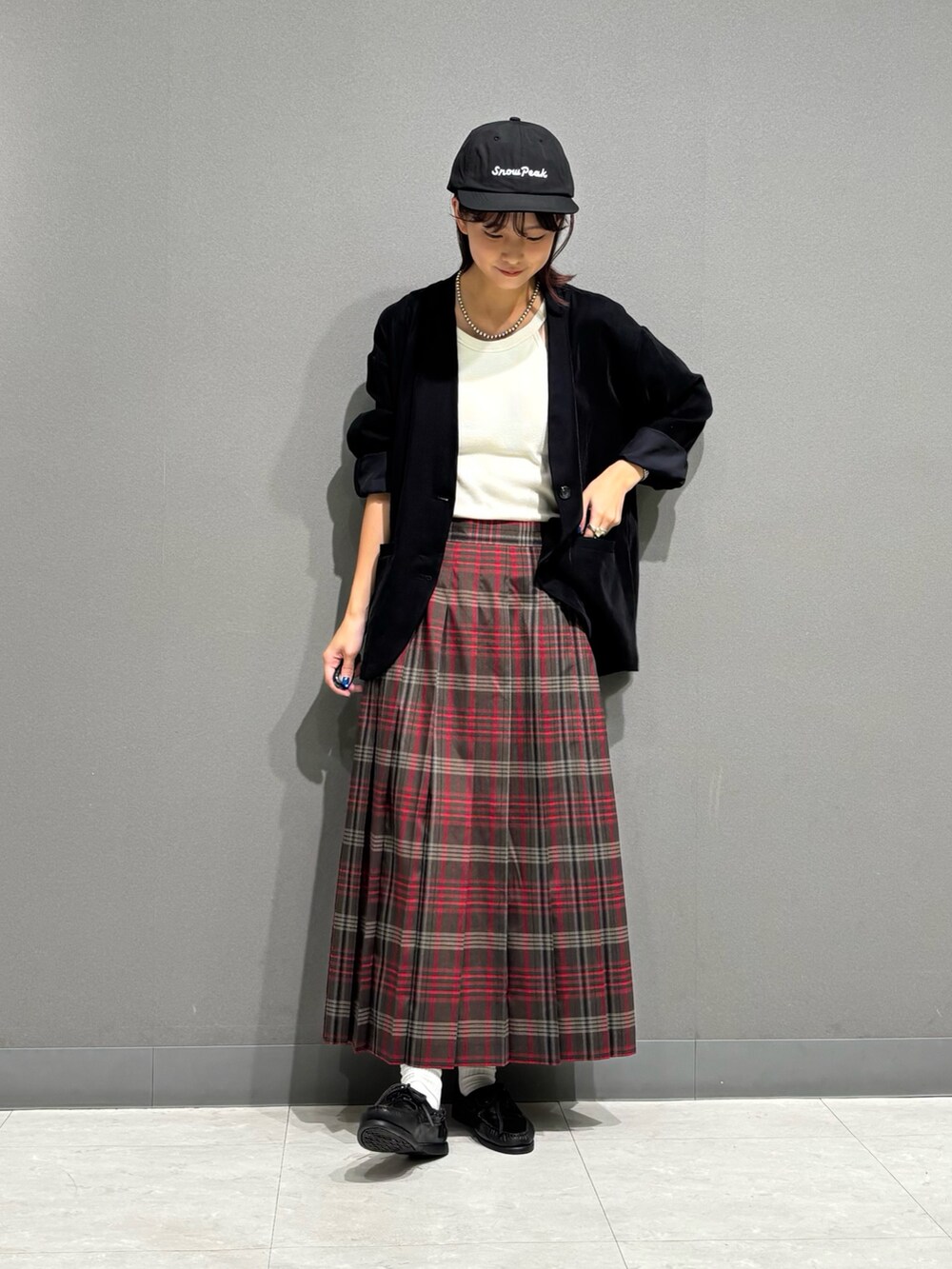 ブラウン系のスカート、ブラック系のノーカラージャケット、ブラック系のキャップを着用したレディースの秋コーディネートの5枚目の写真