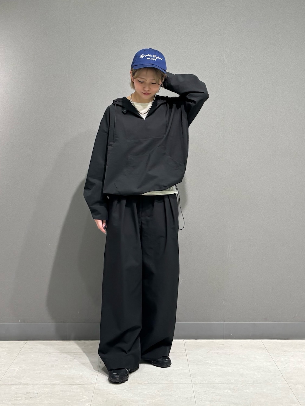 ブラック系のその他アウター、ブラック系のその他パンツ、ブルー系のキャップを着用したレディースの春コーディネートの2枚目の写真