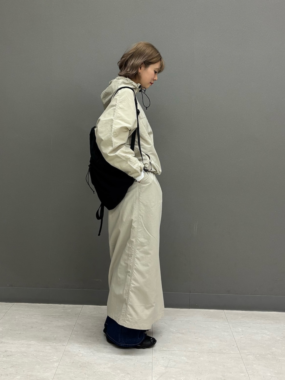 ベージュ系のスカート、ブルー系のデニムパンツ、ブラック系のバックパック/リュックを着用したレディースの冬コーディネートの2枚目の写真