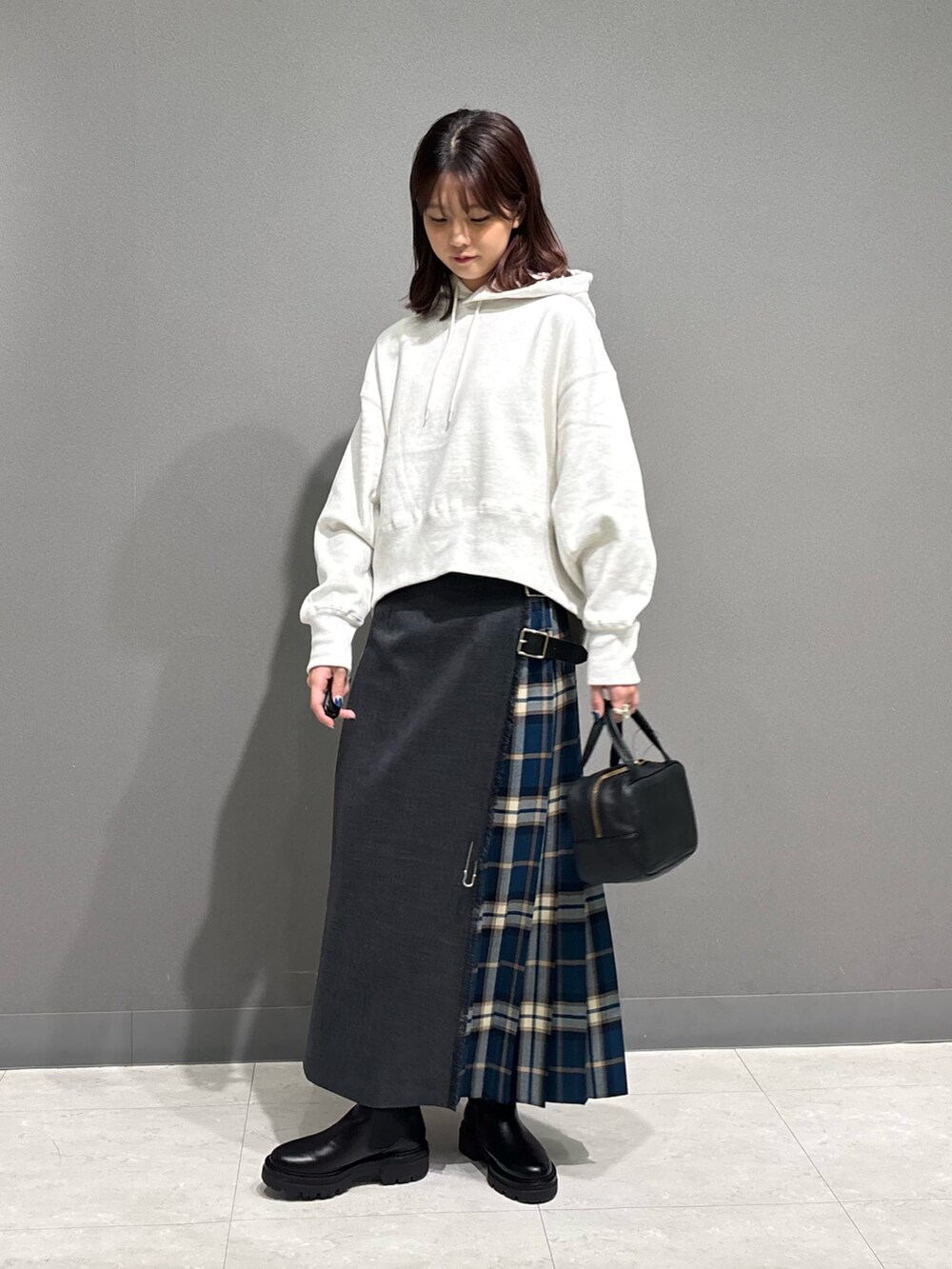 グリーン系のスカート、ブラック系のブーツ、ベージュ系のパーカーを着用したレディースの秋コーディネートの3枚目の写真