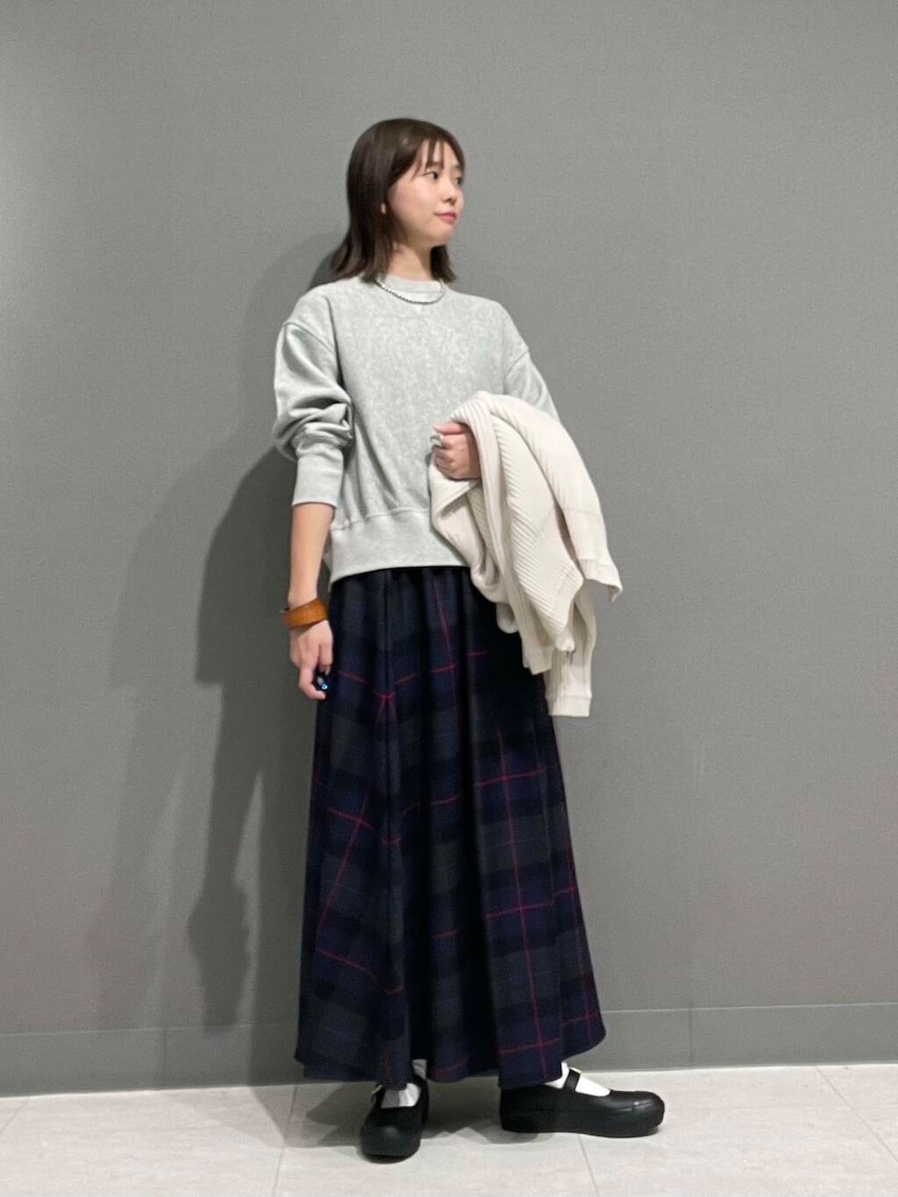 ホワイト系のカーディガン/ボレロ、グレー系のTシャツ/カットソー、ブルー系のスカートを着用したレディースの秋コーディネートの9枚目の写真