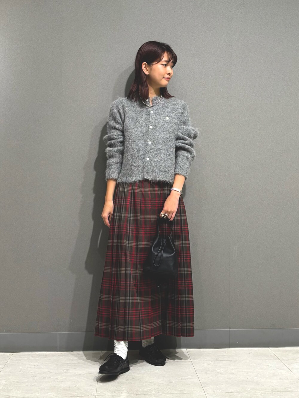 ブラウン系のスカート、グレー系のカーディガン/ボレロ、ブラック系のショルダーバッグを着用したレディースの秋コーディネートの5枚目の写真