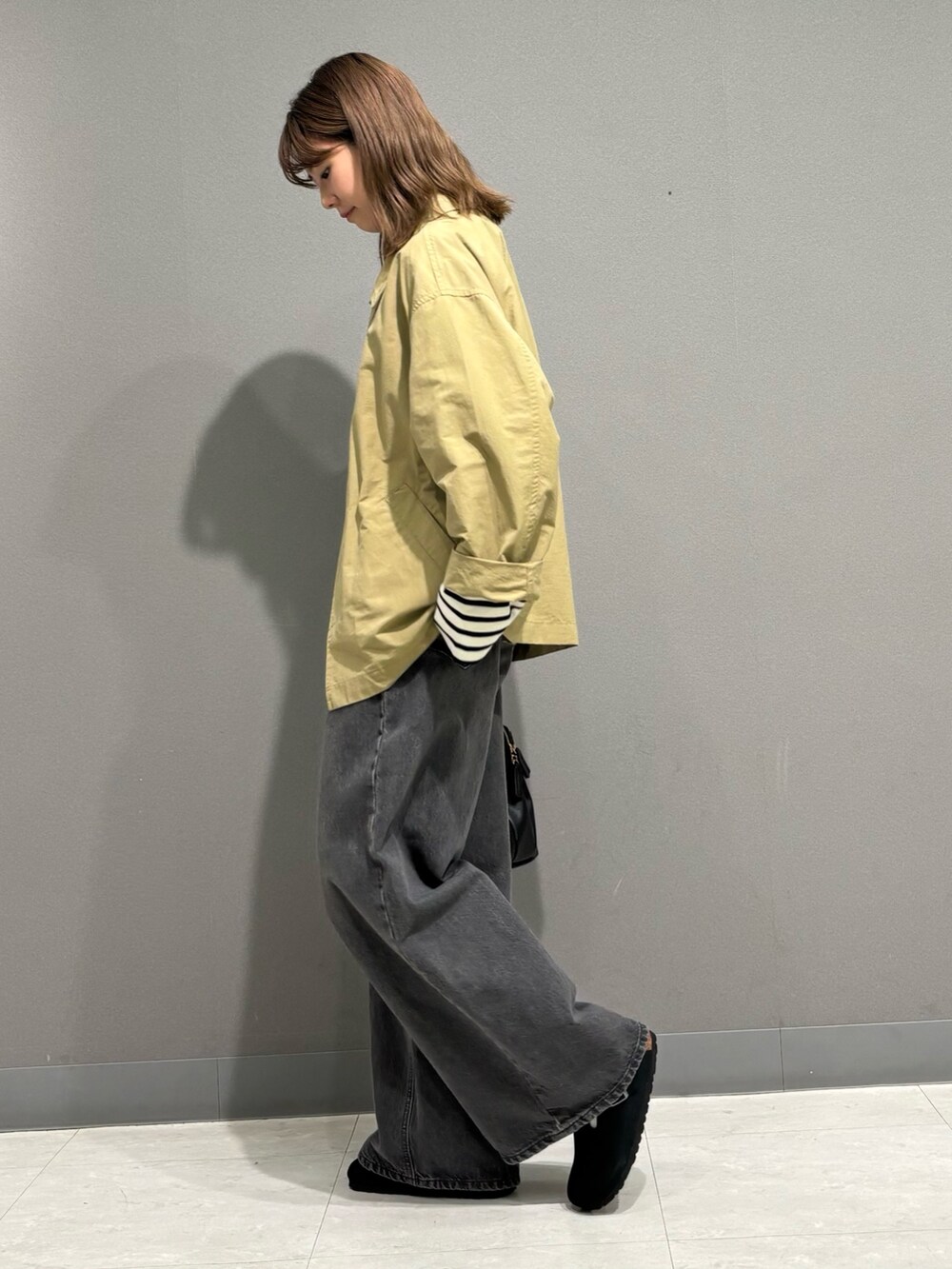 ホワイト系のTシャツ/カットソー、ベージュ系のステンカラーコート、ブラック系のトートバッグを着用したレディースの秋コーディネートの2枚目の写真