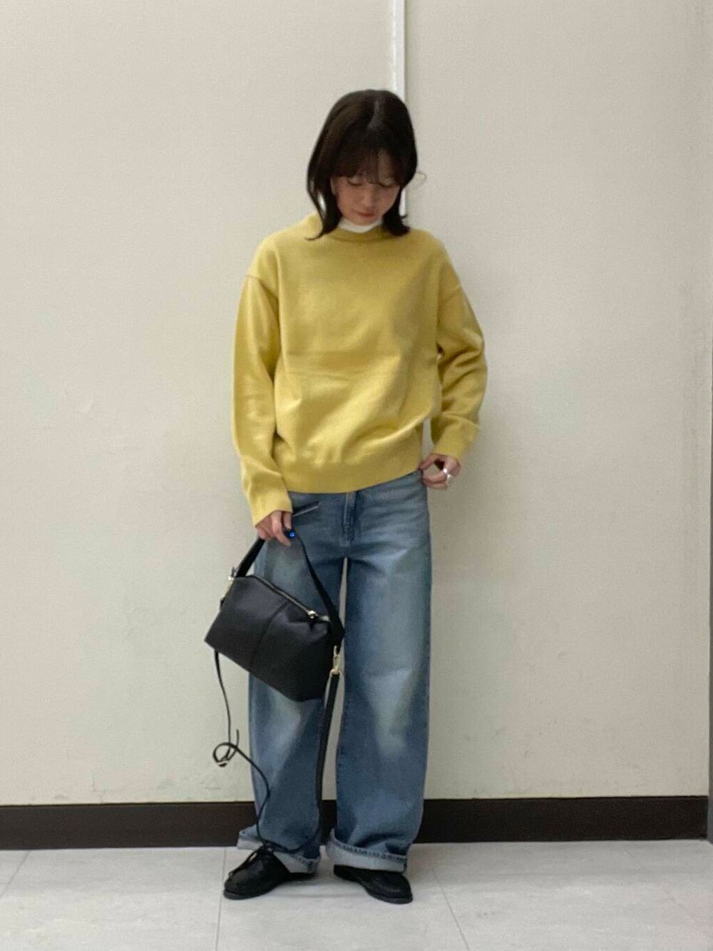 イエロー系のニット/セーター、ブルー系のデニムパンツ、ブラック系のショルダーバッグを着用したレディースの冬コーディネートの3枚目の写真