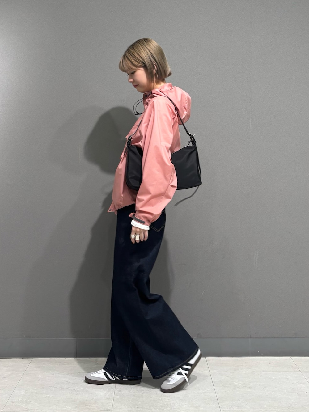 ピンク系のナイロンジャケット、ブルー系のデニムパンツ、ホワイト系のスニーカーを着用したレディースの冬コーディネートの2枚目の写真