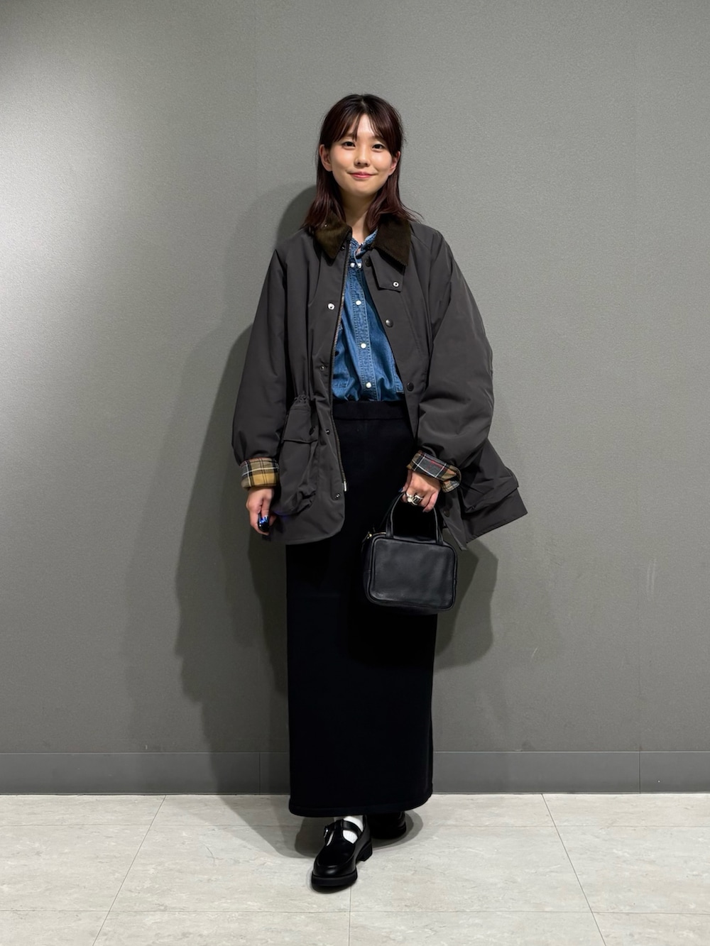 グレー系のその他アウター、ブラック系のローファー、ブラック系のスカートを着用したレディースの秋コーディネートの9枚目の写真