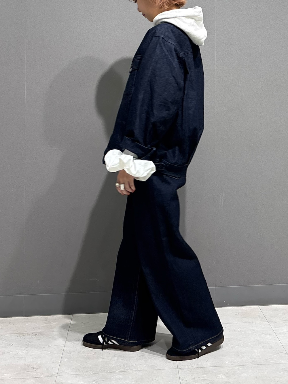 ブルー系のデニムパンツ、ベージュ系のパーカー、ブラック系のスニーカーを着用したレディースの冬コーディネートの4枚目の写真