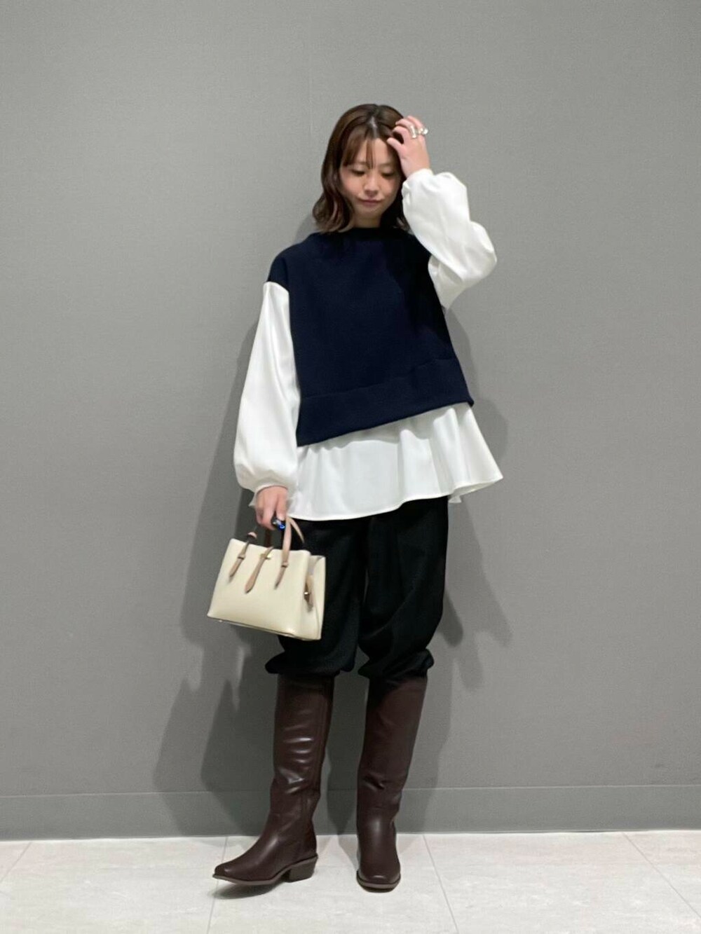 ホワイト系のハンドバッグ、ブラウン系のブーツ、ブラック系のその他パンツを着用したレディースの冬コーディネートの6枚目の写真