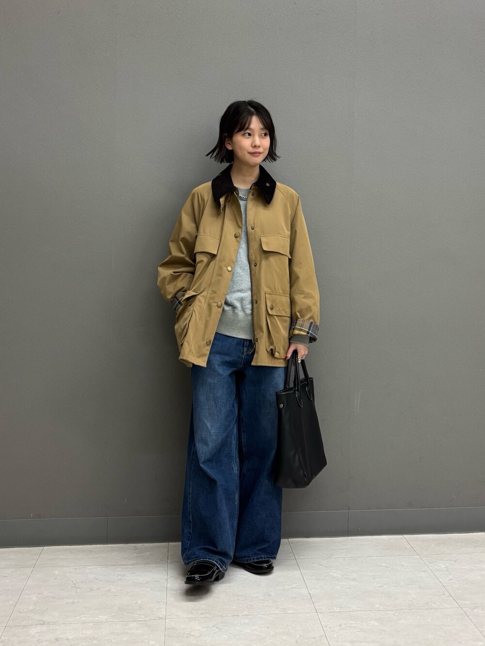 ベージュ系のテーラードジャケット、ブラック系のトートバッグ、ブルー系のデニムパンツを着用したレディースの秋コーディネートの5枚目の写真