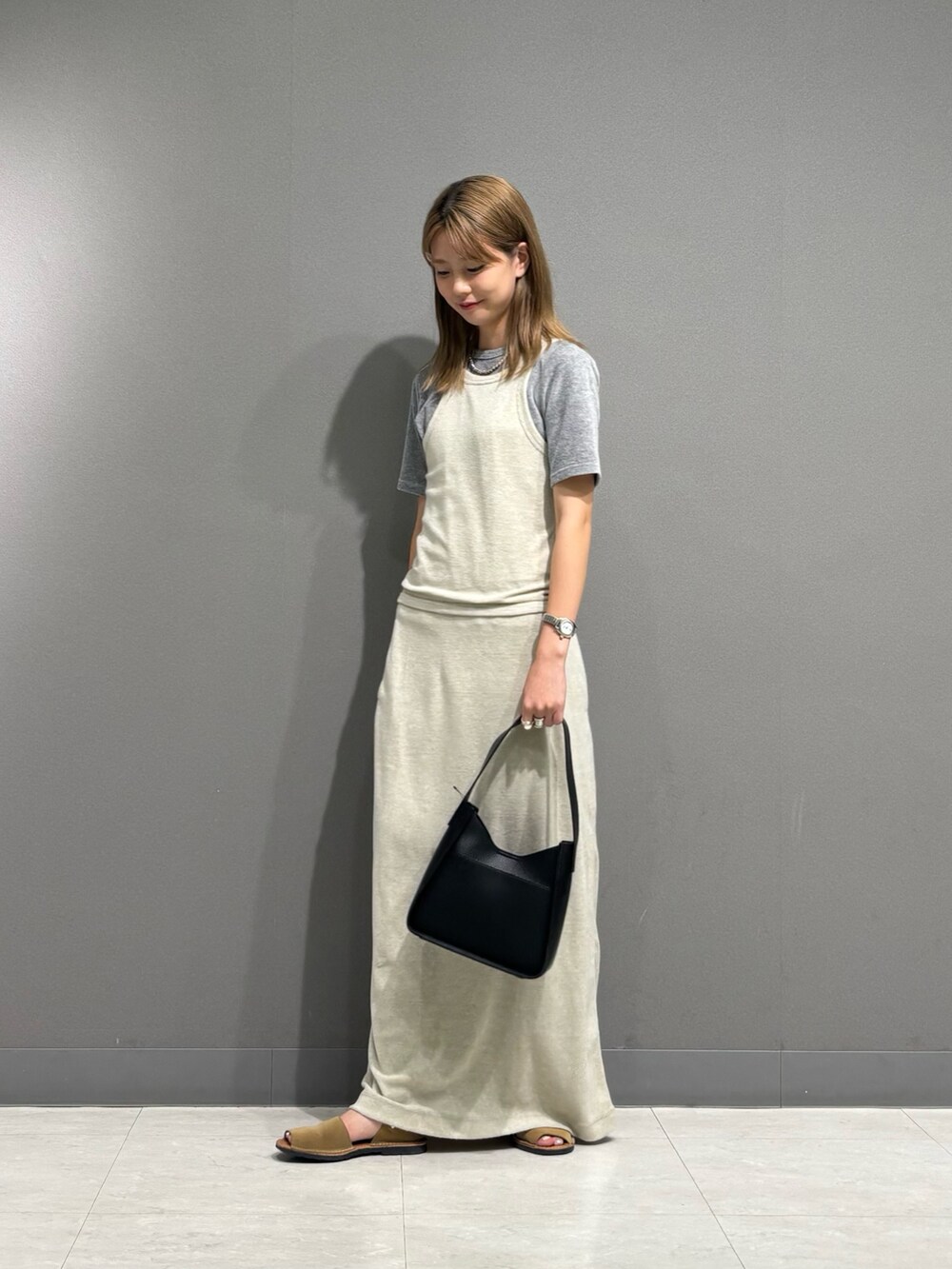 グレー系のTシャツ/カットソー、グレー系のスカート、ブラック系のハンドバッグを着用したレディースの秋コーディネートの4枚目の写真