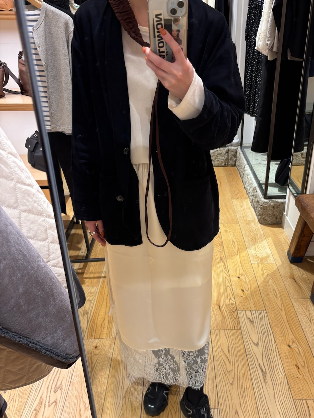 ホワイト系のスカート、ブラック系のノーカラージャケット、ブラウン系のバッグを着用したレディースの冬コーディネートの2枚目の写真