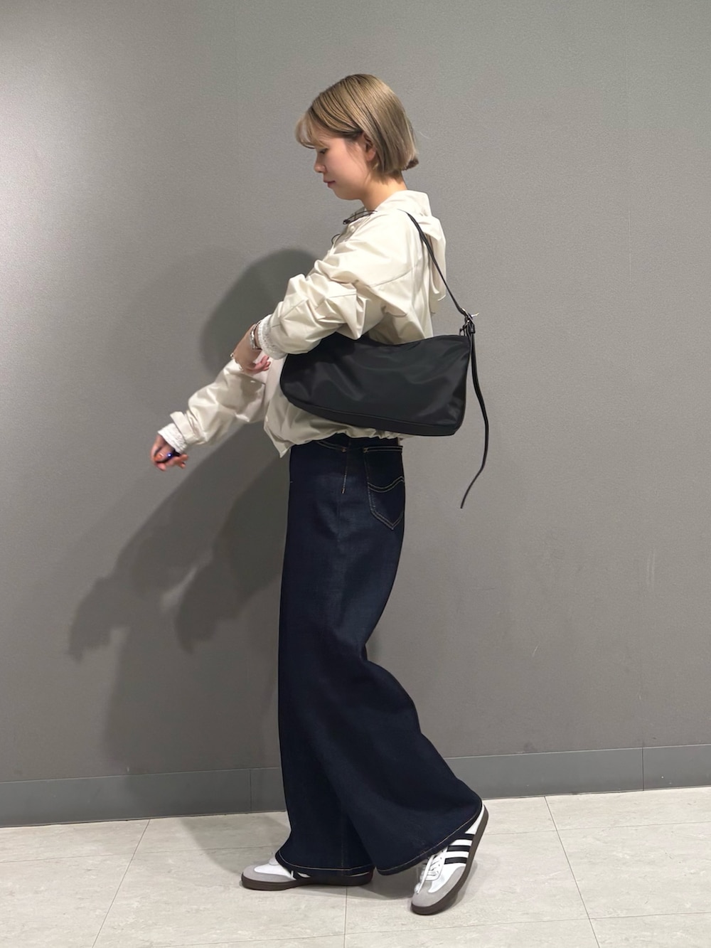 ホワイト系のナイロンジャケット、ブルー系のデニムパンツ、ブラック系のショルダーバッグを着用したレディースの冬コーディネートの6枚目の写真