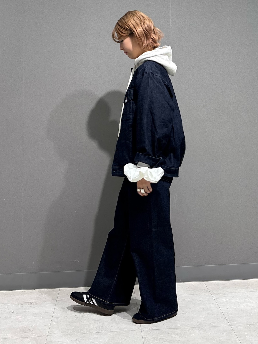 ブルー系のデニムパンツ、ベージュ系のパーカー、ブラック系のスニーカーを着用したレディースの冬コーディネートの3枚目の写真