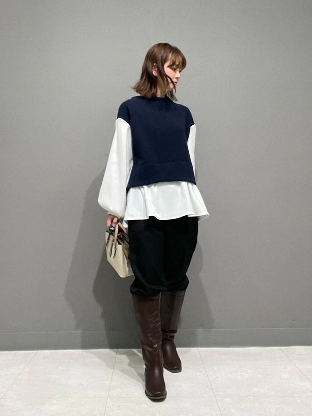 ホワイト系のハンドバッグ、ブラウン系のブーツ、ブラック系のその他パンツを着用したレディースの冬コーディネートの7枚目の写真