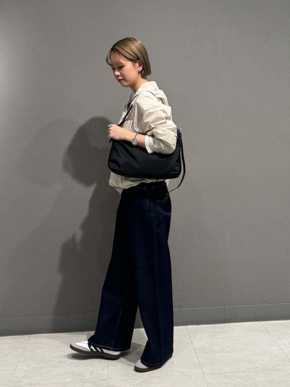 ホワイト系のナイロンジャケット、ブルー系のデニムパンツ、ブラック系のショルダーバッグを着用したレディースの冬コーディネートの7枚目の写真