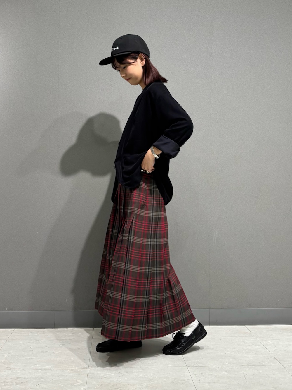 ブラウン系のスカート、ブラック系のノーカラージャケット、ブラック系のキャップを着用したレディースの秋コーディネートの4枚目の写真