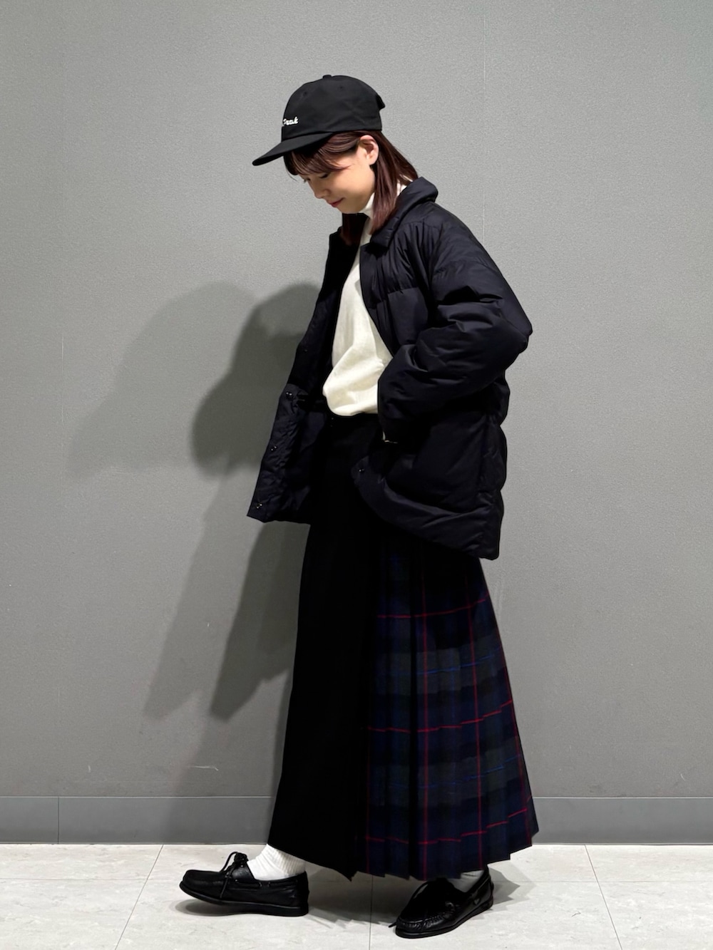 グレー系のスカート、ブラック系のダウンジャケット/コート、ベージュ系のスウェットを着用したレディースの秋コーディネートの4枚目の写真