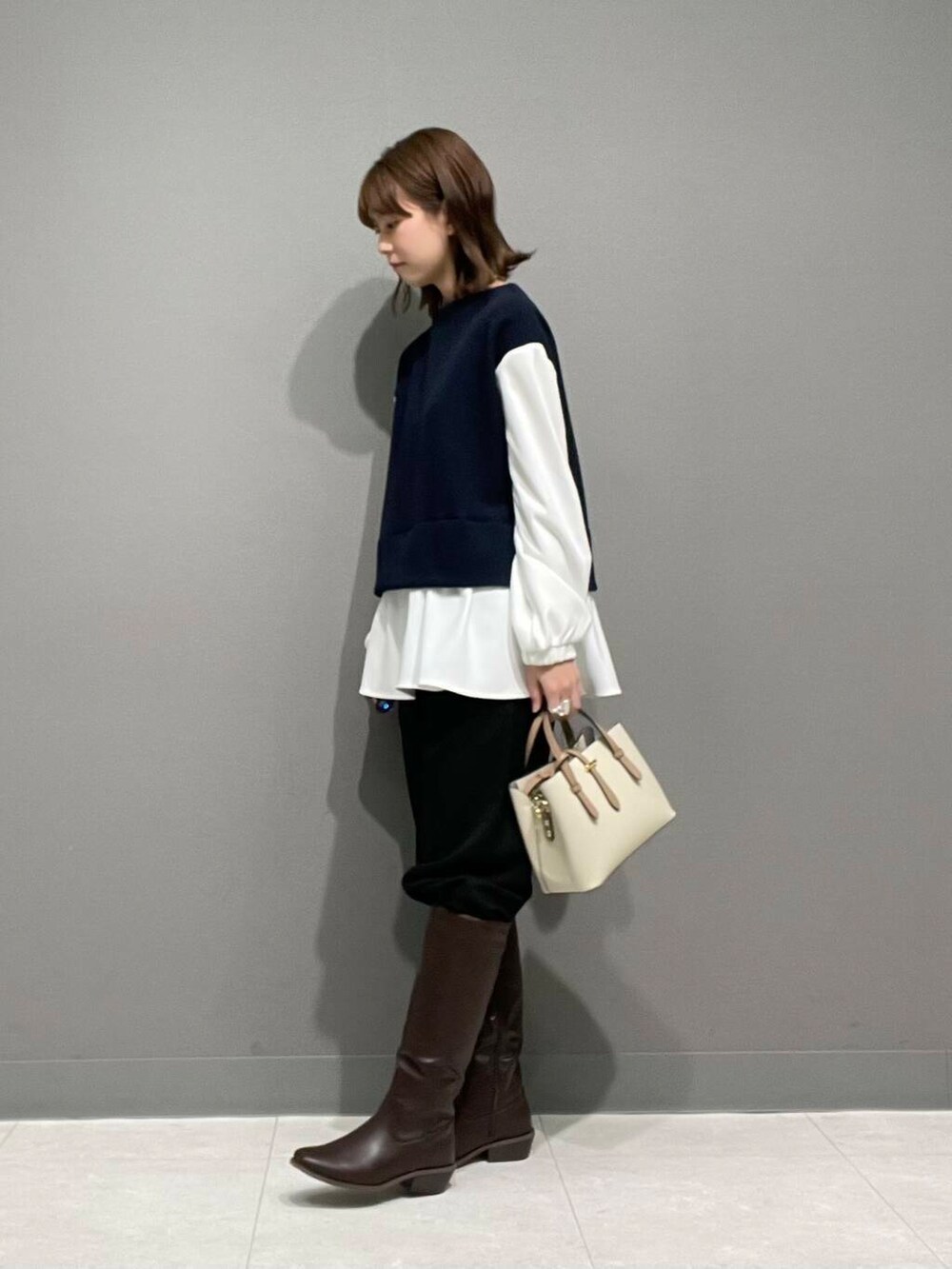 ホワイト系のハンドバッグ、ブラウン系のブーツ、ブラック系のその他パンツを着用したレディースの冬コーディネートの5枚目の写真