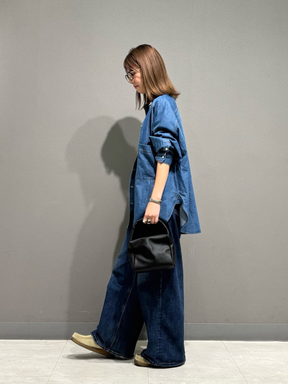 ブルー系のシャツ/ブラウス、ブラック系のTシャツ/カットソー、ブラック系のハンドバッグを着用したレディースの秋コーディネートの4枚目の写真