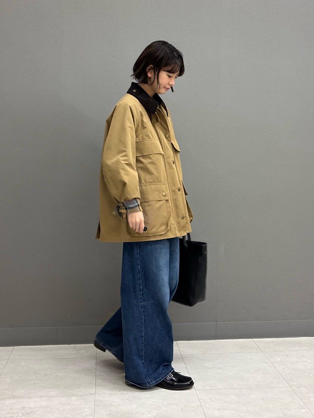 ベージュ系のテーラードジャケット、ブラック系のトートバッグ、ブルー系のデニムパンツを着用したレディースの秋コーディネートの4枚目の写真