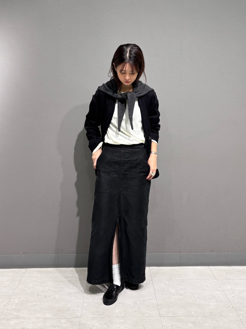 ブラック系のノーカラージャケット、グレー系のマフラーを着用したレディースの秋コーディネートの2枚目の写真