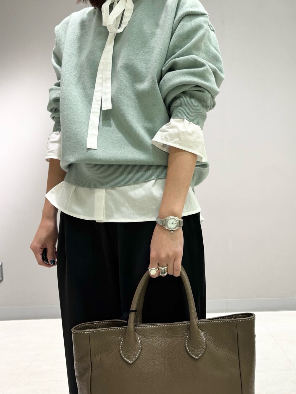 ホワイト系のシャツ/ブラウス、グリーン系のニット/セーター、グレー系のトートバッグを着用したレディースの秋コーディネートの5枚目の写真
