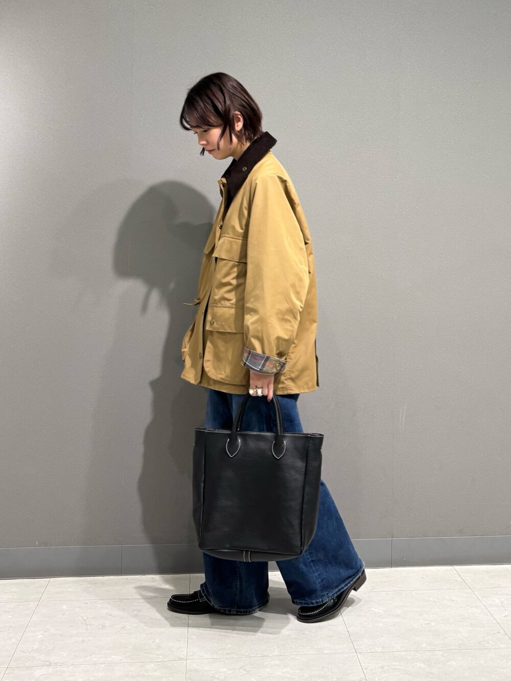 ベージュ系のテーラードジャケット、ブラック系のトートバッグ、ブルー系のデニムパンツを着用したレディースの秋コーディネートの2枚目の写真