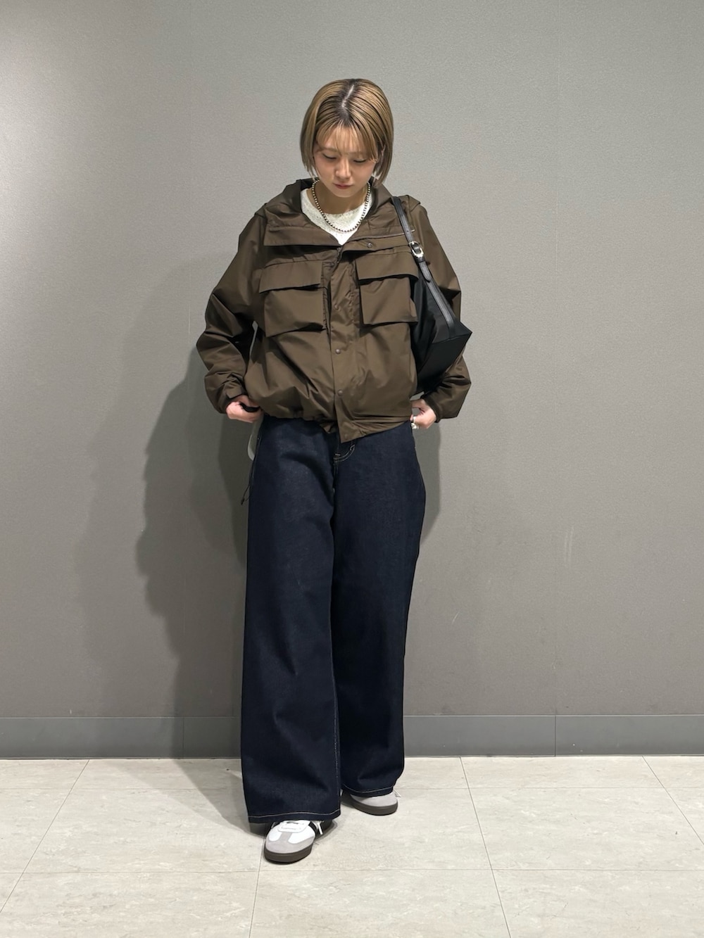ブラウン系のナイロンジャケット、ブルー系のデニムパンツ、ホワイト系のスニーカーを着用したレディースの冬コーディネートの3枚目の写真