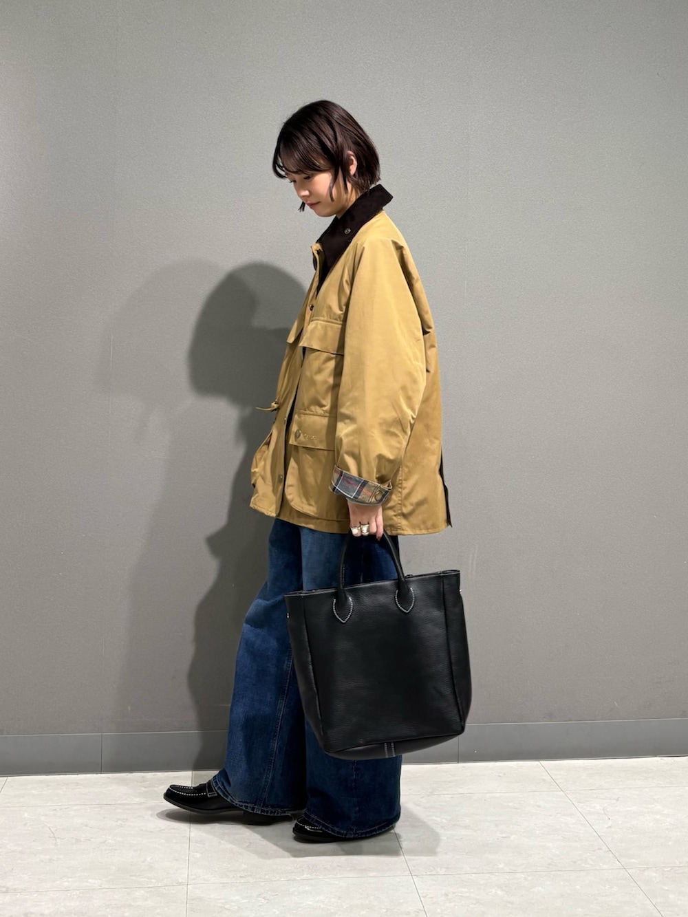 ベージュ系のテーラードジャケット、ブラック系のトートバッグ、ブルー系のデニムパンツを着用したレディースの秋コーディネートの3枚目の写真