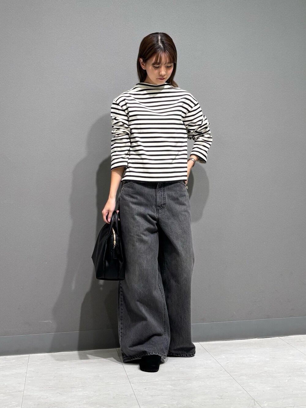 ホワイト系のTシャツ/カットソー、ベージュ系のステンカラーコート、ブラック系のトートバッグを着用したレディースの秋コーディネートの3枚目の写真