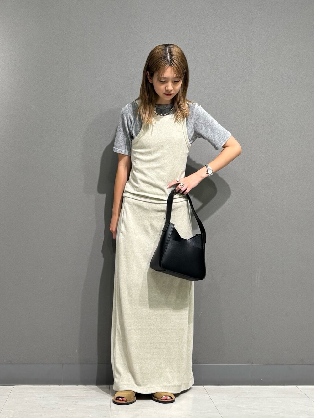 グレー系のTシャツ/カットソー、グレー系のスカート、ブラック系のハンドバッグを着用したレディースの秋コーディネートの2枚目の写真