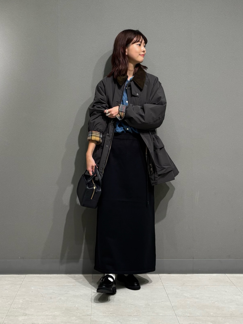 グレー系のその他アウター、ブラック系のローファー、ブラック系のスカートを着用したレディースの秋コーディネートの6枚目の写真
