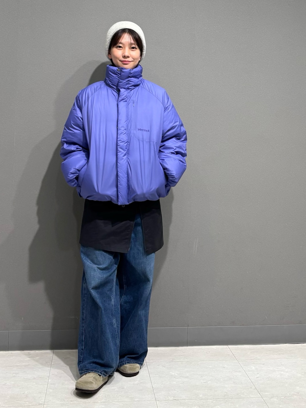 パープル系のダウンジャケット/コート、ブルー系のデニムパンツ、ベージュ系のサンダルを着用したレディースの秋コーディネートの2枚目の写真