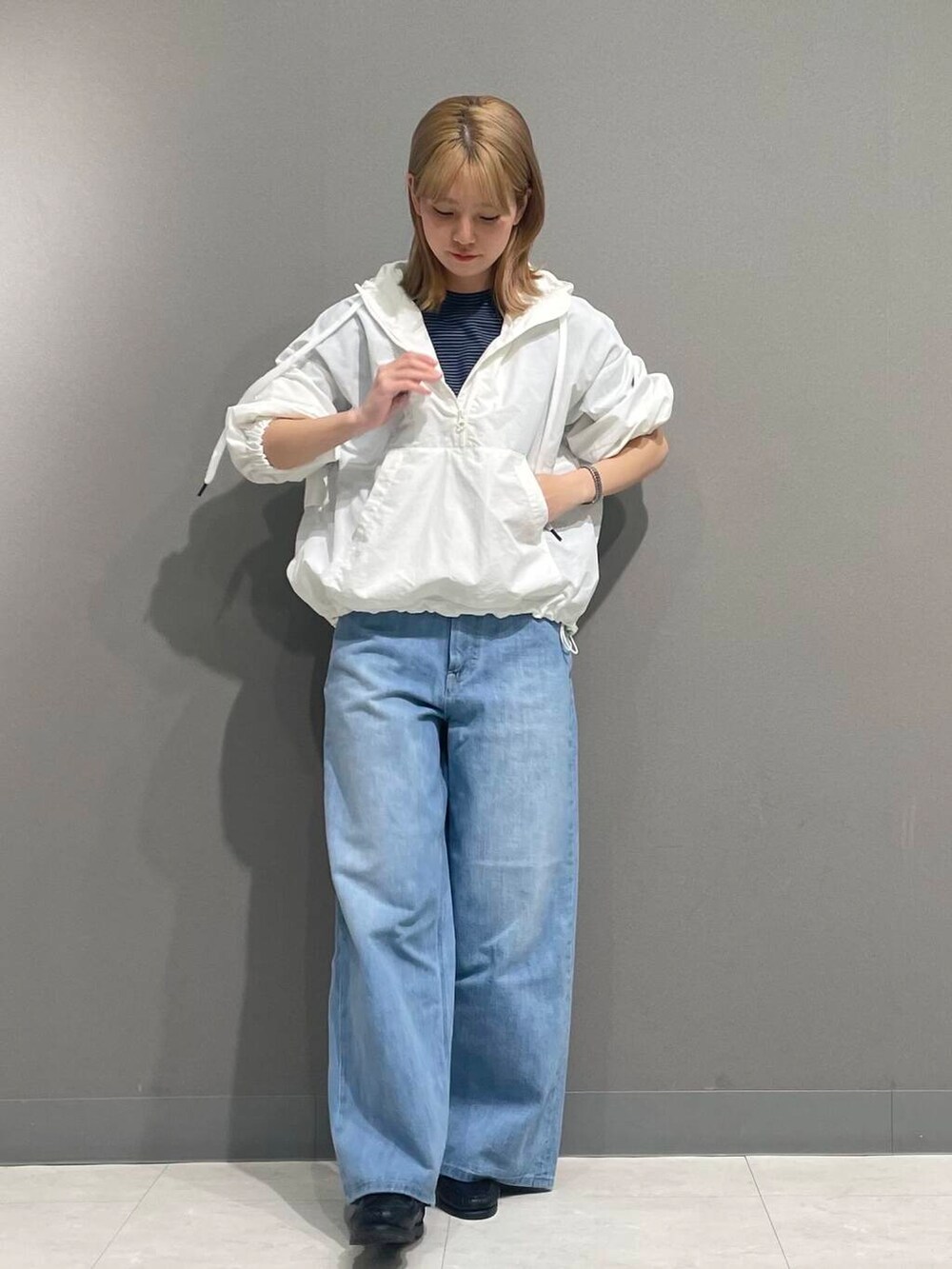 ブルー系のデニムパンツ、ホワイト系のパーカーを着用したレディースの春コーディネートの3枚目の写真