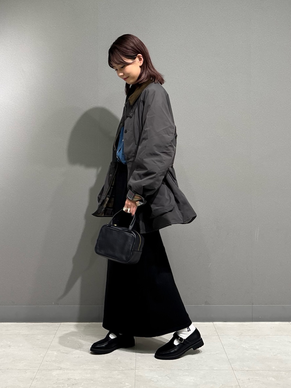 グレー系のその他アウター、ブラック系のローファー、ブラック系のスカートを着用したレディースの秋コーディネートの4枚目の写真