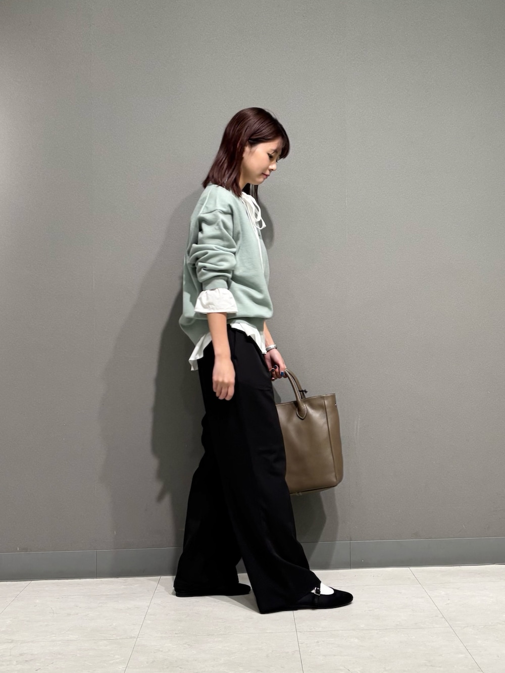 ホワイト系のシャツ/ブラウス、グリーン系のニット/セーター、グレー系のトートバッグを着用したレディースの秋コーディネートの3枚目の写真