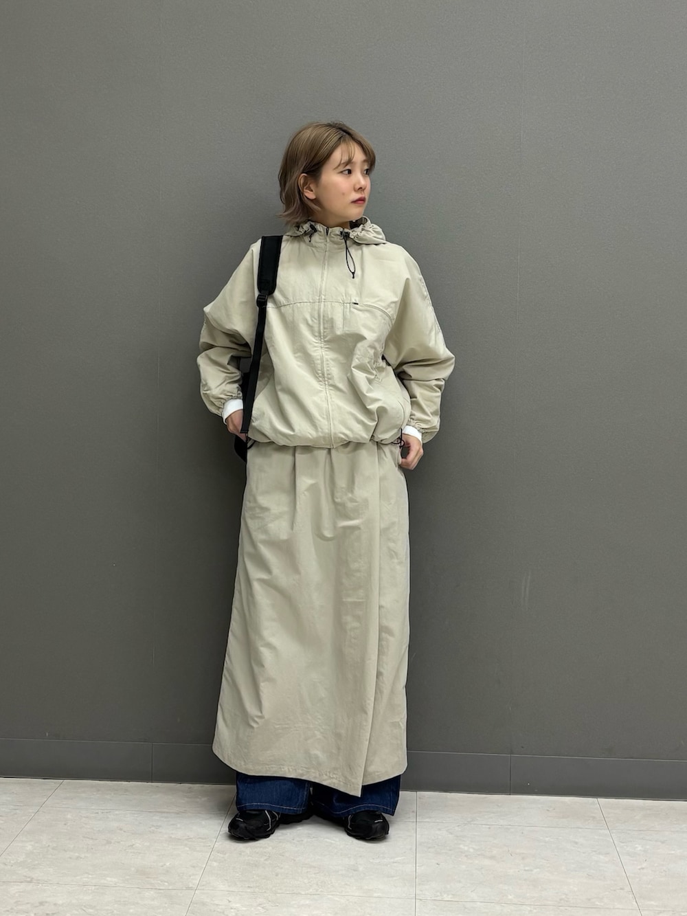 ベージュ系のスカート、ブルー系のデニムパンツ、ブラック系のバックパック/リュックを着用したレディースの冬コーディネートの3枚目の写真