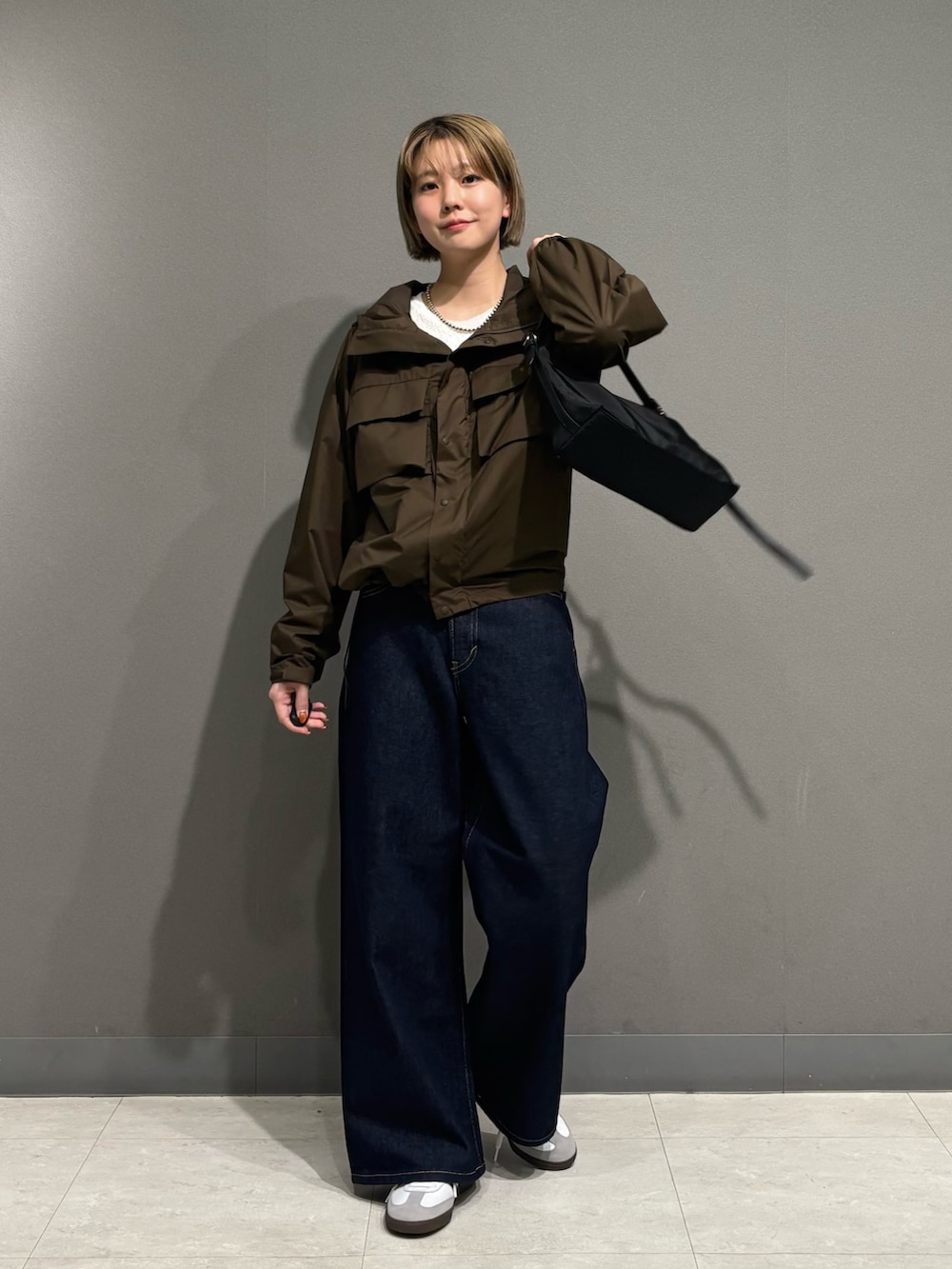 ブラウン系のナイロンジャケット、ブルー系のデニムパンツ、ホワイト系のスニーカーを着用したレディースの冬コーディネートの6枚目の写真