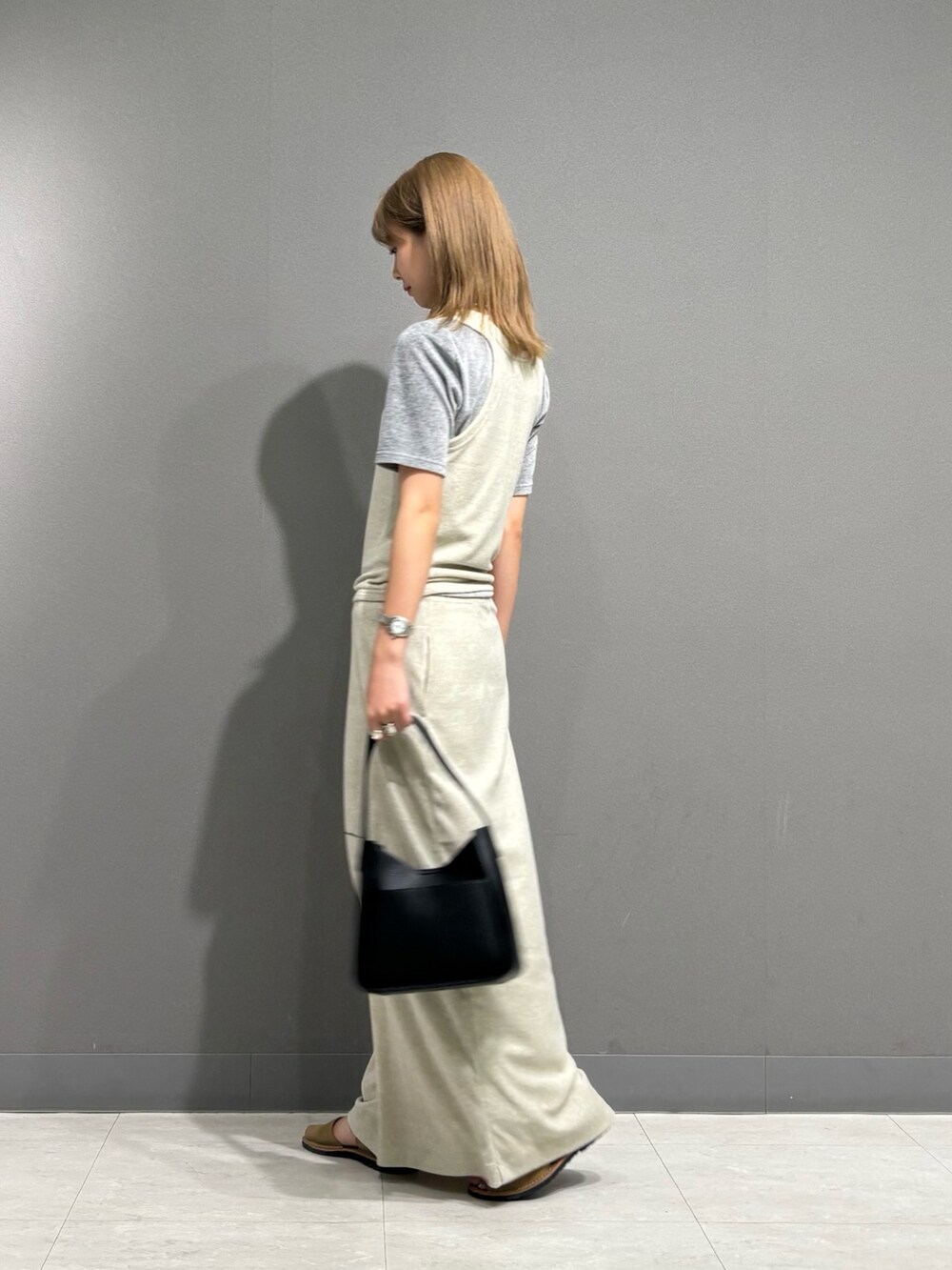 グレー系のTシャツ/カットソー、グレー系のスカート、ブラック系のハンドバッグを着用したレディースの秋コーディネートの6枚目の写真