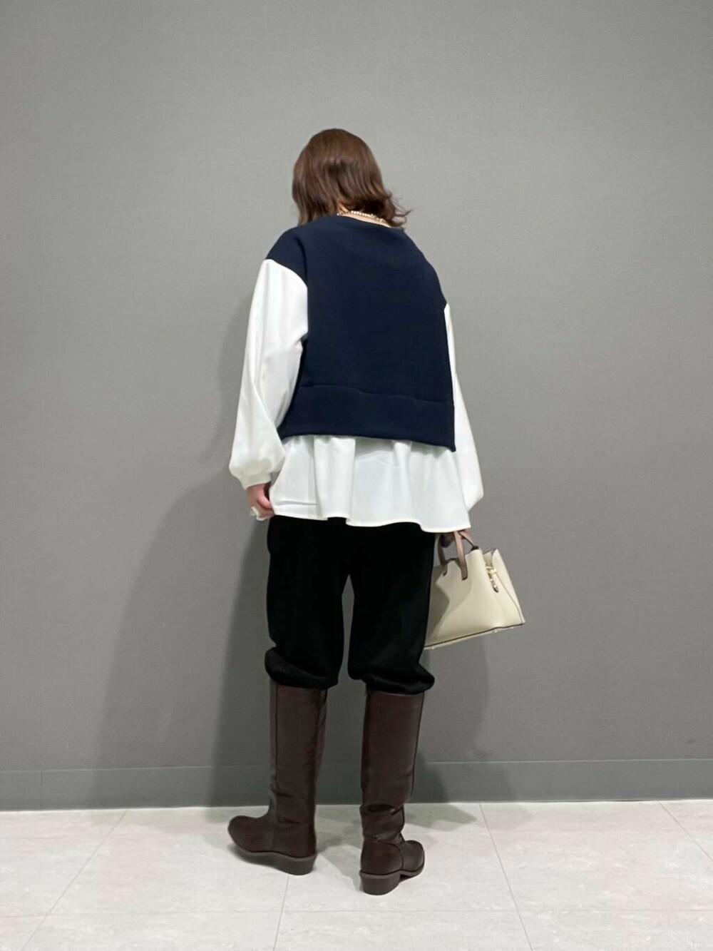 ホワイト系のハンドバッグ、ブラウン系のブーツ、ブラック系のその他パンツを着用したレディースの冬コーディネートの8枚目の写真