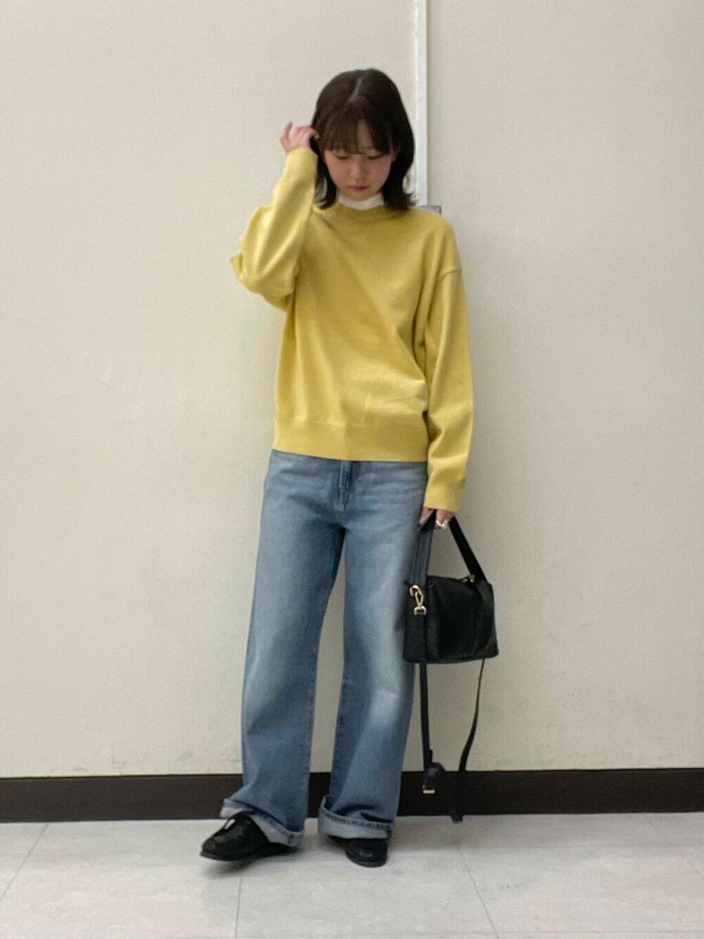 イエロー系のニット/セーター、ブルー系のデニムパンツ、ブラック系のショルダーバッグを着用したレディースの冬コーディネートの5枚目の写真
