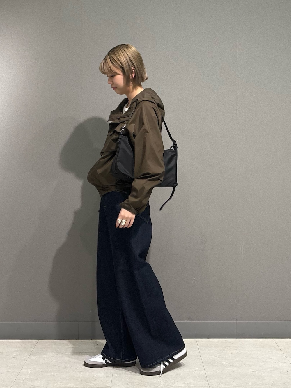 ブラウン系のナイロンジャケット、ブルー系のデニムパンツ、ホワイト系のスニーカーを着用したレディースの冬コーディネートの5枚目の写真