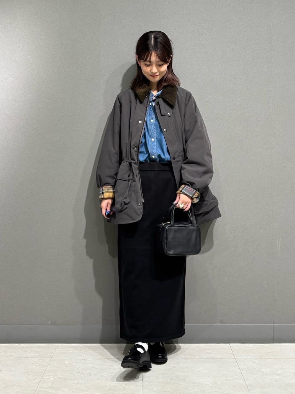 グレー系のその他アウター、ブラック系のローファー、ブラック系のスカートを着用したレディースの秋コーディネートの8枚目の写真