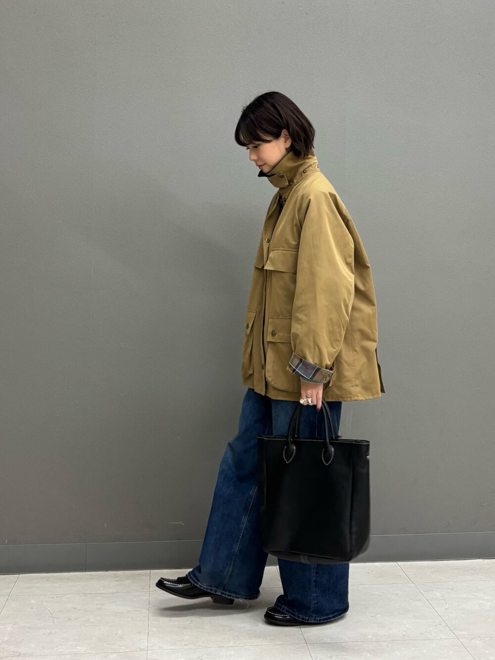 ベージュ系のテーラードジャケット、ブラック系のトートバッグ、ブルー系のデニムパンツを着用したレディースの秋コーディネートの6枚目の写真