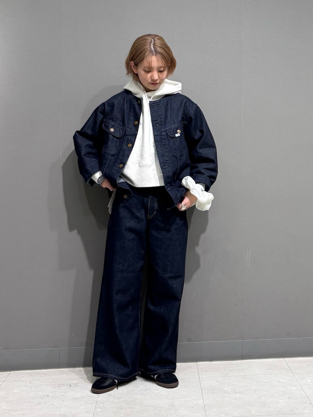 ブルー系のデニムパンツ、ベージュ系のパーカー、ブラック系のスニーカーを着用したレディースの冬コーディネートの2枚目の写真