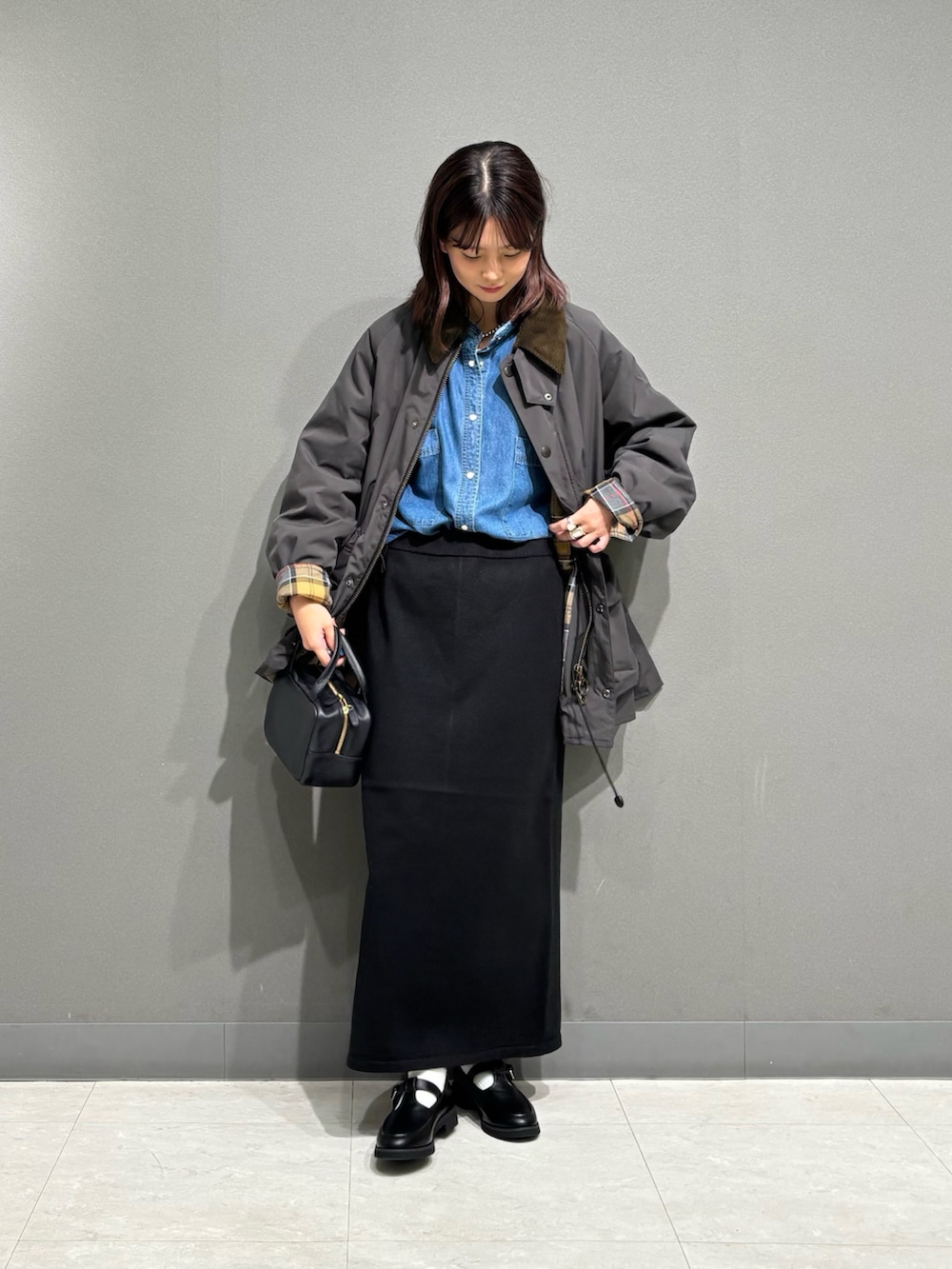グレー系のその他アウター、ブラック系のローファー、ブラック系のスカートを着用したレディースの秋コーディネートの7枚目の写真