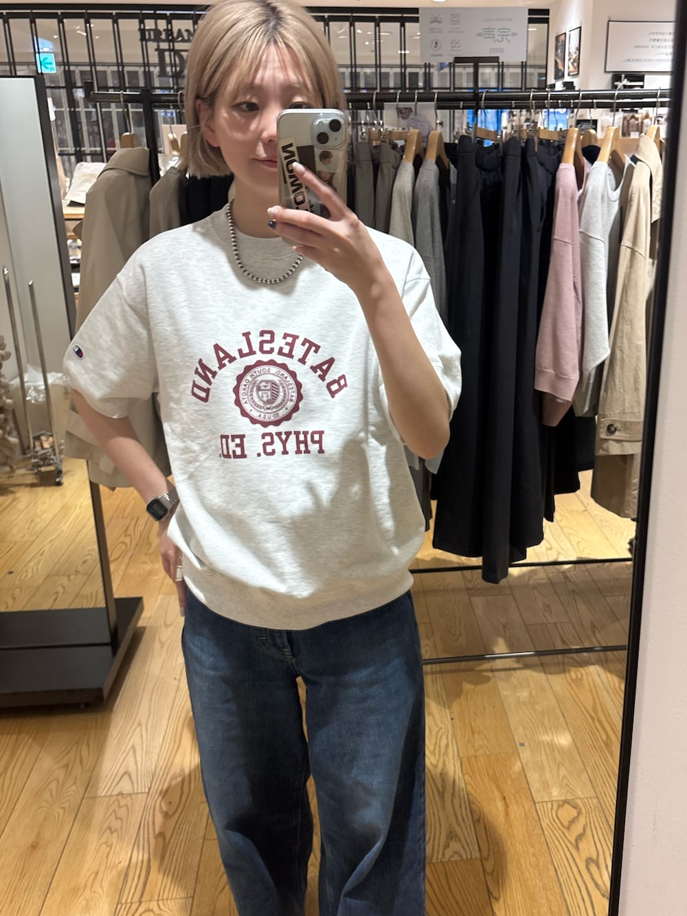 ベージュ系のスウェット、ブルー系のデニムパンツを着用したレディースの春コーディネートの2枚目の写真