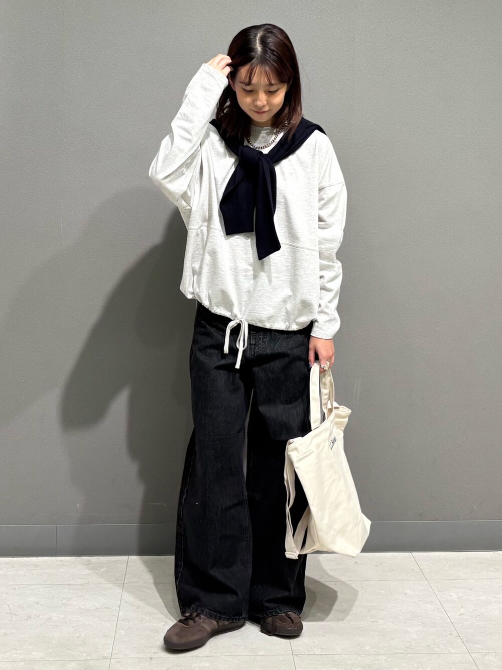 ベージュ系のTシャツ/カットソー、ブルー系のカーディガン/ボレロ、ブラック系のデニムパンツを着用したレディースの秋コーディネートの2枚目の写真