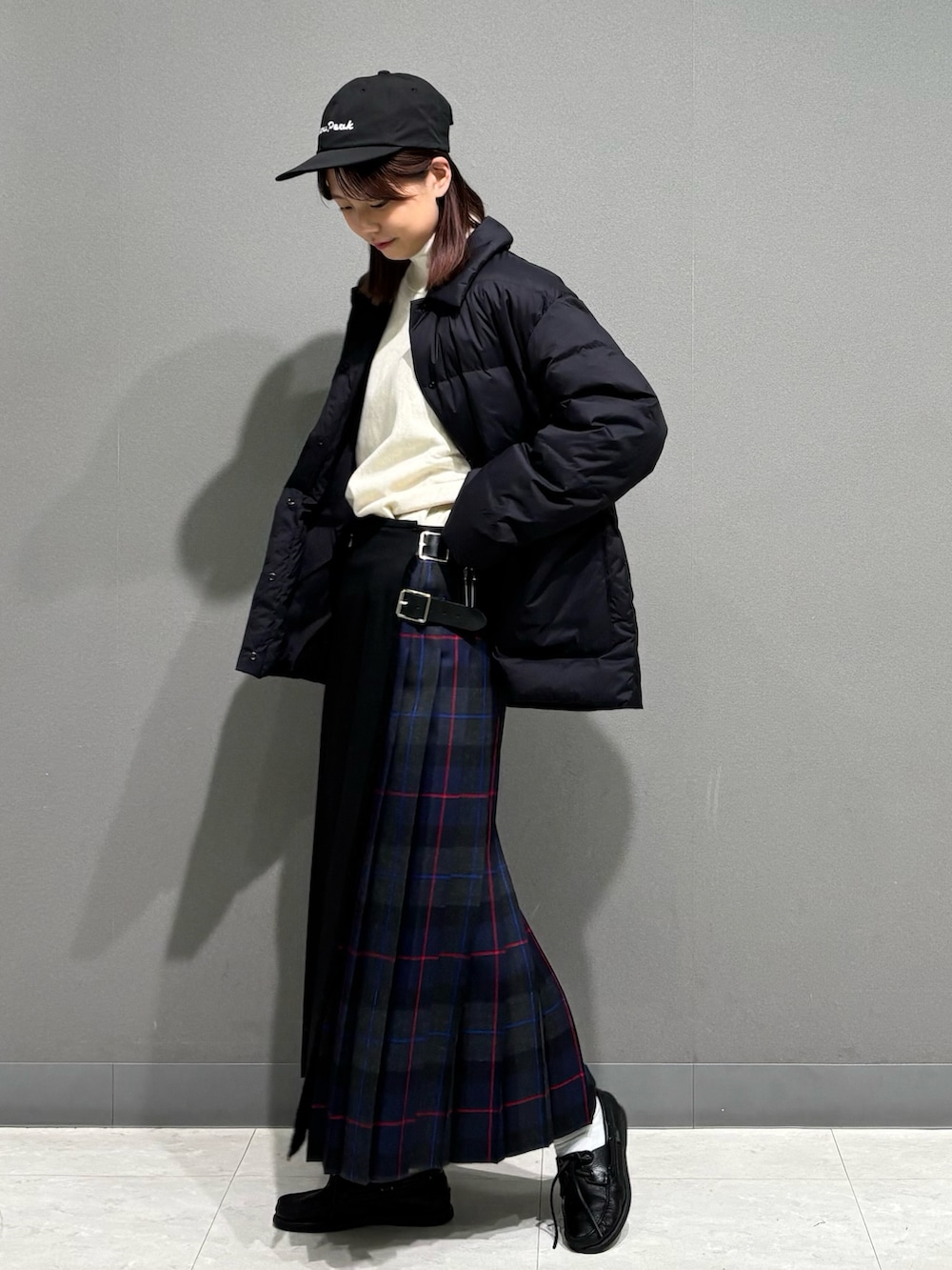 グレー系のスカート、ブラック系のダウンジャケット/コート、ベージュ系のスウェットを着用したレディースの秋コーディネートの6枚目の写真